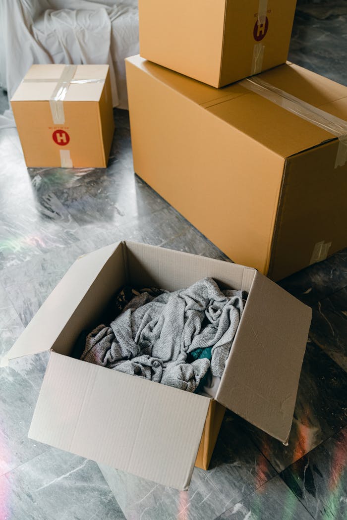 services-05 From above of cardboard boxes with packed items placed on floor in new apartment
